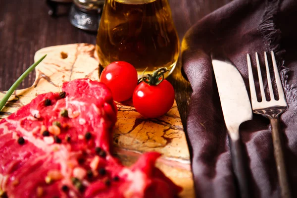 Pedaço de carne crua com ervas e azeite — Fotografia de Stock