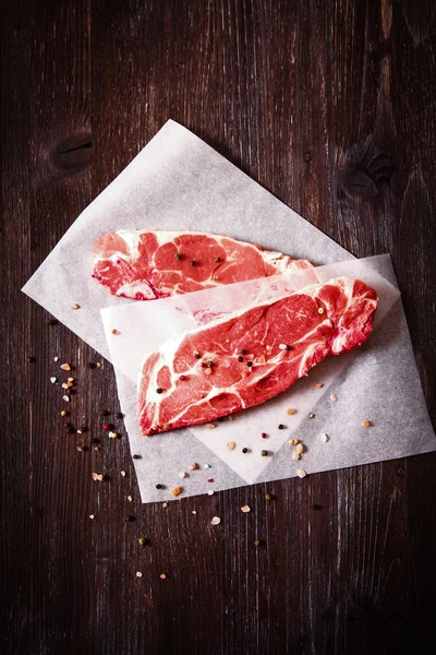 Шматок сирого м'яса на білому папері з перцем — стокове фото