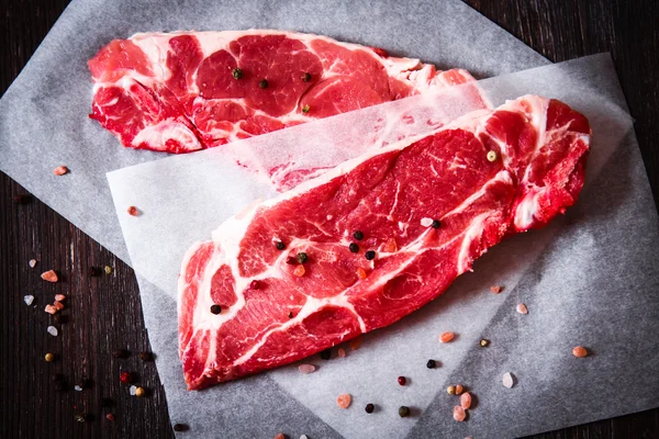 Pedaço de carne crua em papel branco com pimenta — Fotografia de Stock