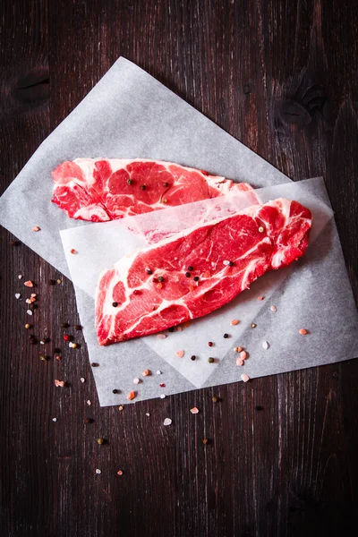 Kawałek surowego mięsa na białym papierze z pieprzem — Zdjęcie stockowe
