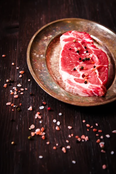 Pezzo di carne cruda di manzo sul piatto con peperoni matelicheskoy — Foto Stock