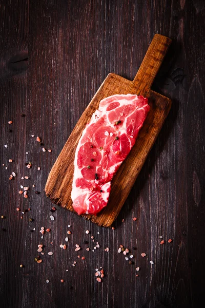 Pezzo di carne cruda di manzo su una tavola di legno con pepe — Foto Stock