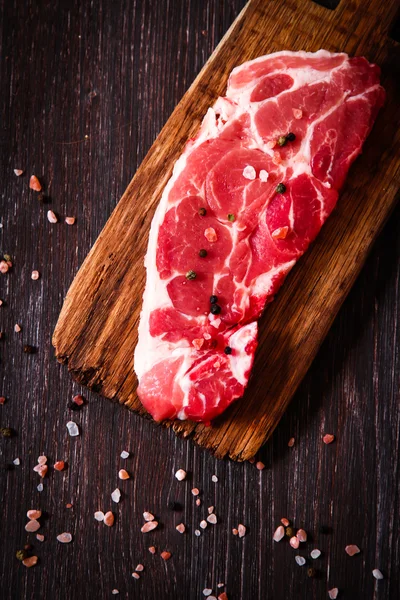 Pezzo di carne cruda di manzo su una tavola di legno con pepe — Foto Stock