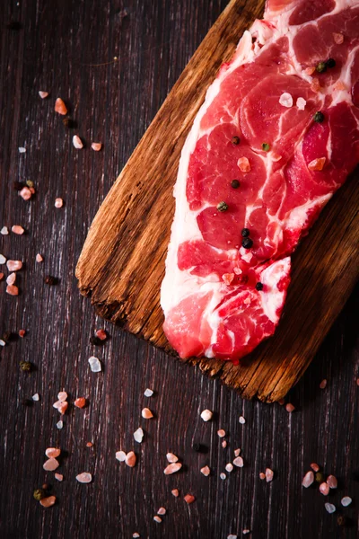 Pezzo di carne cruda di manzo su una tavola di legno con pepe — Foto Stock