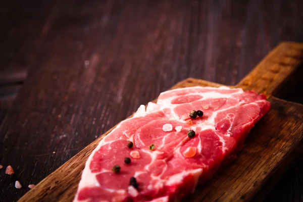 Kus syrové maso hovězí na dřevěném prkénku s pepřem — Stock fotografie