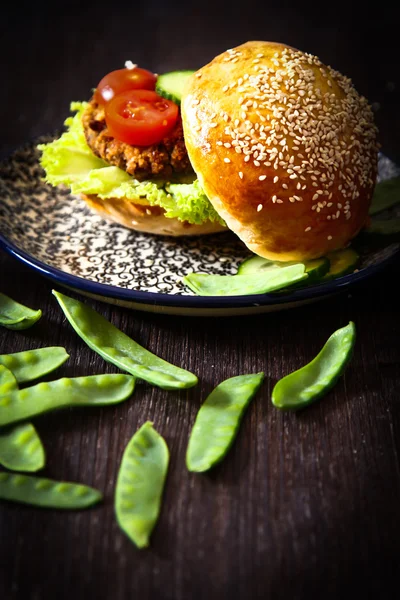 homemade veggie burger in a bun with sesame seeds of beer.