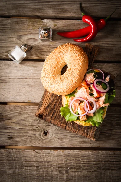 Bagel à la laitue et saumon cuit sur une planche de bois , — Photo