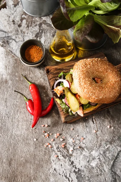 Bagel mit Salat und gebackenem Lachs auf einem Holzbrett, — Stockfoto