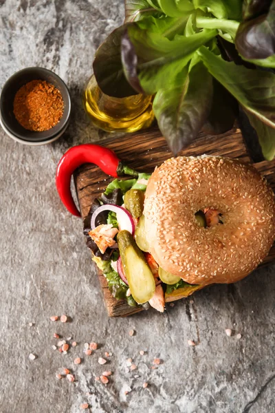 Bagel à la laitue et saumon cuit sur une planche de bois , — Photo