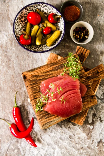 Bife de atum em uma tábua de madeira com pimenta e pepino — Fotografia de Stock