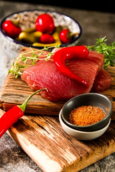 Bife de atum em uma tábua de madeira com pimenta e pepino — Fotografia de Stock