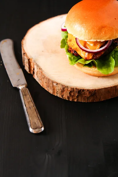 Deliciosa hamburguesa casera fresca en el tablero de servir oscuro con picante — Foto de Stock