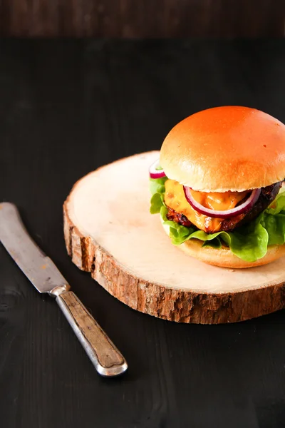 Delicious fresh homemade burger on dark serving board with spicy — Stock Photo, Image