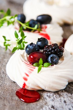 Meringue dessert Pavlova cake with fresh berries on a gray stone clipart