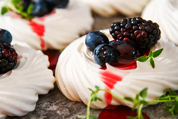 Meringue dessert Pavlova cake with fresh berries on a gray stone