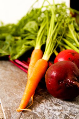 Eski bir ahşap masa üzerinde yeşil yaprakları ile organik kırmızı pancar. Pas