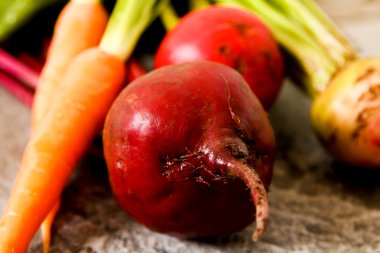 Eski bir ahşap masa üzerinde yeşil yaprakları ile organik kırmızı pancar. Pas