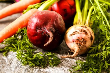 Eski bir ahşap masa üzerinde yeşil yaprakları ile organik kırmızı pancar. Pas