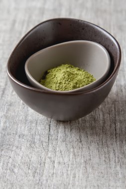 Matcha çay bir küçük kahverengi plaka kuru. Gri ahşap arka plan
