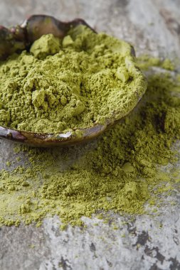 Matcha çay bir küçük kahverengi plaka kuru. Koyu seramik arka plan