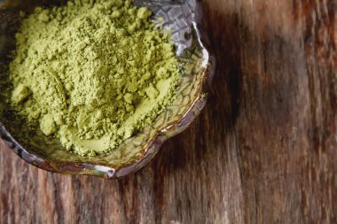 Matcha çay bir küçük kahverengi plaka kuru. Koyu ahşap arka plan. Sayfanın Üstü