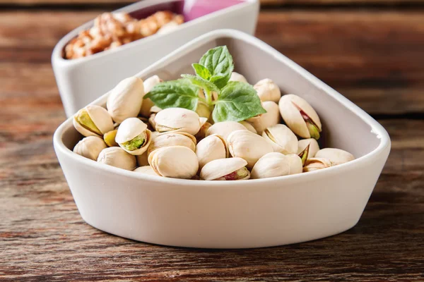 Pistachios in the shell and walnuts with a mint on dark wooden b — Stock Photo, Image