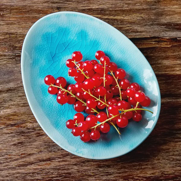 Красная спелая смородина на голубой тарелке. Темный деревянный фон. Вид сверху — стоковое фото