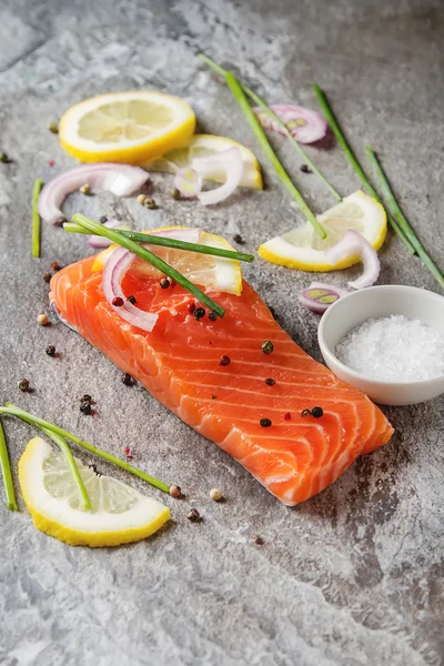 One piece of fresh salmon with lemon pepper and salt. Grey stone — Stock Photo, Image