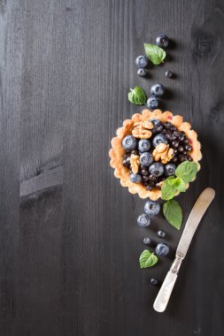 Ev yapımı yaban mersini tart, ceviz ve koyu ahşap masa nane. F