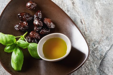 Yeşil Konfit zeytin ve zeytin yağı bir kapta. Koyu arka plan.