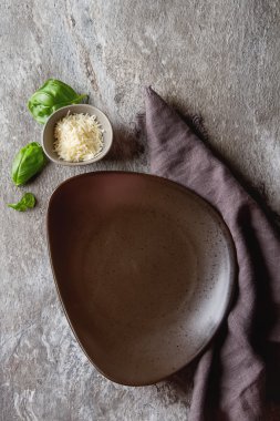 Parmesan peynirli gri tabak, taze fesleğen. Boş kahverengi plaka.