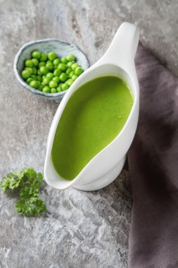 Bezelye çorbası püresi beyaz bir tureen içinde. Taş kayrak arka plan