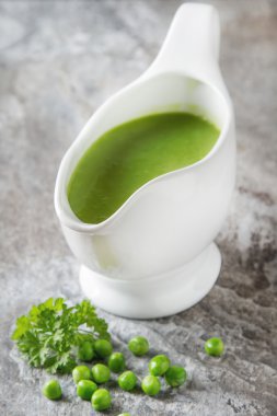 Bezelye çorbası püresi beyaz bir tureen içinde. Taş kayrak arka plan