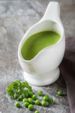 Bezelye çorbası püresi beyaz bir tureen içinde. Taş kayrak arka plan