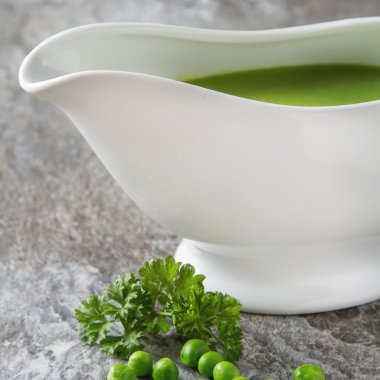 Bezelye çorbası püresi beyaz bir tureen içinde. Taş kayrak arka plan. Meydanı