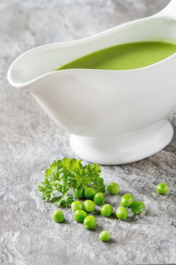 Bezelye çorbası püresi beyaz bir tureen içinde. Taş kayrak arka plan