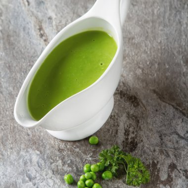 Bezelye çorbası püresi beyaz bir tureen içinde. Taş kayrak arka plan. Meydanı