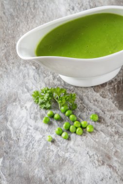 Bezelye çorbası püresi beyaz bir tureen içinde. Taş kayrak arka plan