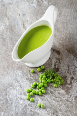 Bezelye çorbası püresi beyaz bir tureen içinde. Taş kayrak arka plan