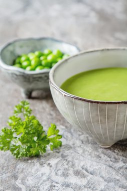 Maydanoz dekorasyonu ile eski bir tabak içinde püre bezelye çorbası. Taş sl