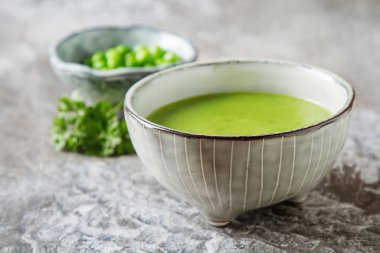 Maydanoz dekorasyonu ile eski bir tabak içinde püre bezelye çorbası. Taş sl