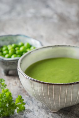 Maydanoz dekorasyonu ile eski bir tabak içinde püre bezelye çorbası. Taş sl