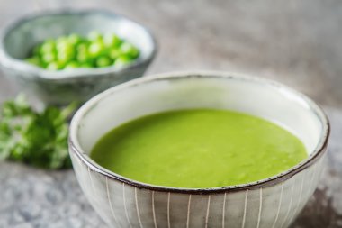 Maydanoz dekorasyonu ile eski bir tabak içinde püre bezelye çorbası. Taş sl