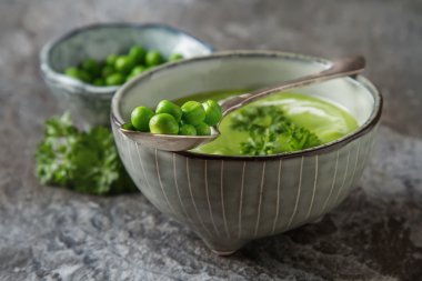 Maydanoz dekorasyonu ile eski bir tabak içinde püre bezelye çorbası. Taş sl
