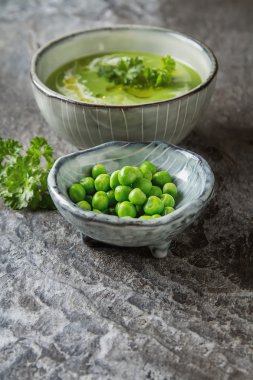Maydanoz dekorasyonu ile eski bir tabak içinde püre bezelye çorbası. Taş sl