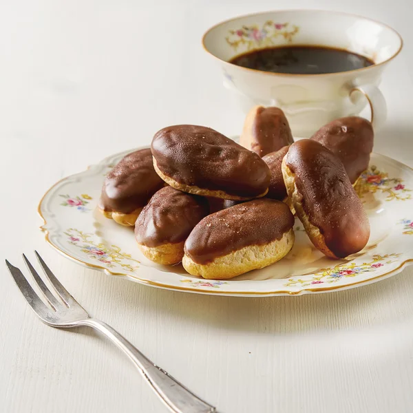 Bolo de chocolate francês, eclairs com uma xícara de café preto quente em — Fotografia de Stock