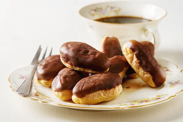 Französischer Schokoladenkuchen, Eclairs mit einer Tasse heißen schwarzen Kaffees in — Stockfoto