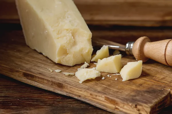 Pedaço de queijo parmesão italiano com uma faca. Backgro de madeira escura — Fotografia de Stock