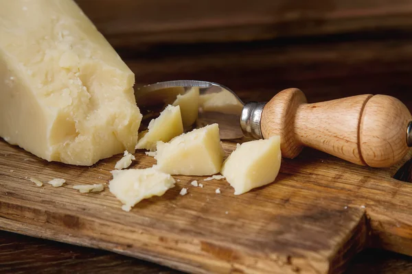 Pedaço de queijo parmesão italiano com uma faca. Backgro de madeira escura — Fotografia de Stock