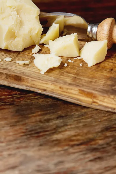 Pedaço de queijo parmesão italiano com uma faca. Backgro de madeira escura — Fotografia de Stock